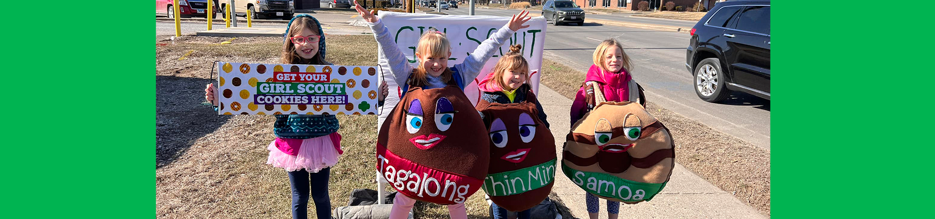  girl scouts selling girl scout cookies at a drive through cookie booth 