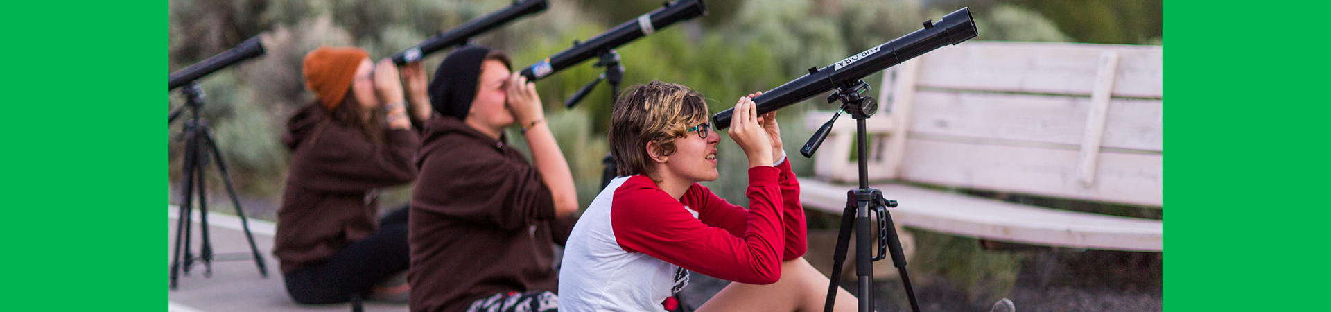  girl scouts looking up into the sky with telescopes 