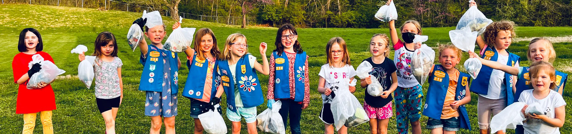  girl scout daisies posing with trash bags full of trash they cleaned up from a park 