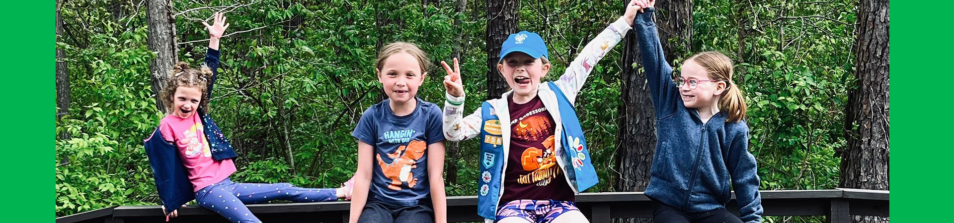  girl scouts sitting on a bridge making fun poses 